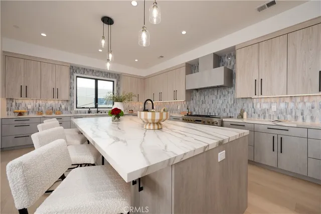 a large kitchen with kitchen island a large counter top a sink stainless steel appliances and cabinets