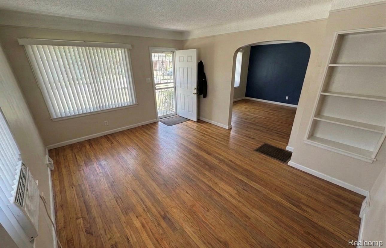 Entryway featuring arched walkways, a textured ceiling, and dark wood finished floors