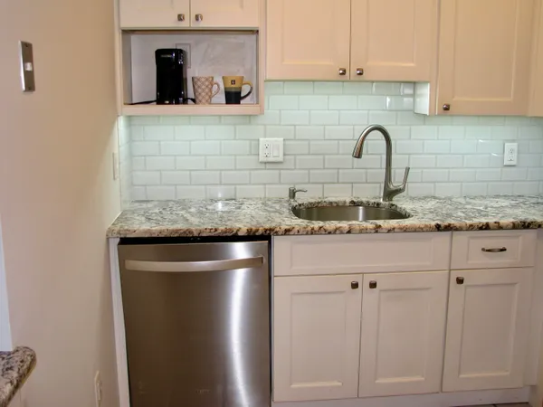 a kitchen with granite countertop white cabinets and stainless steel appliances