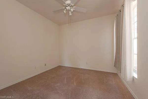 an empty room with a window and a fan