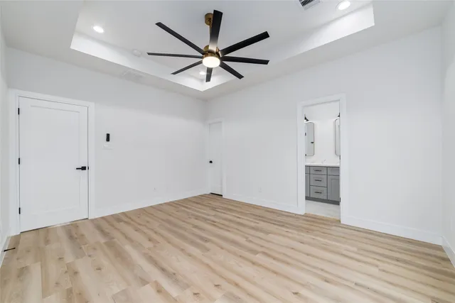 an empty room with wooden floor and ceiling fan