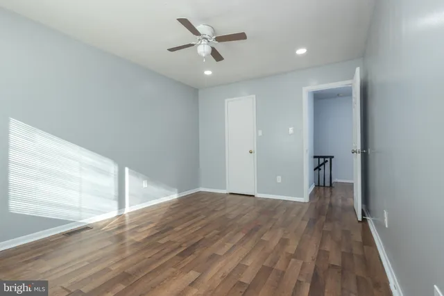 a view of a big room with wooden floor a ceiling fan and windows