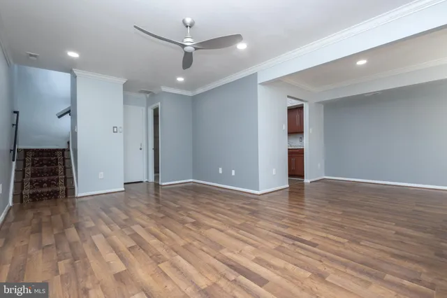 an empty room with wooden floor and a ceiling fan
