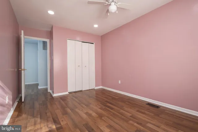 an empty room with wooden floor and fan