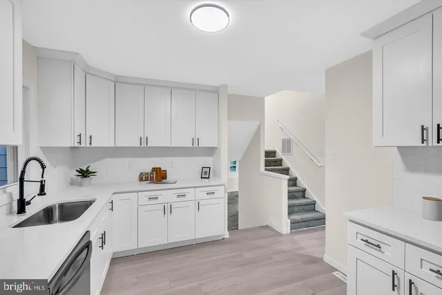 a kitchen with white cabinets a sink a stove and wooden floor