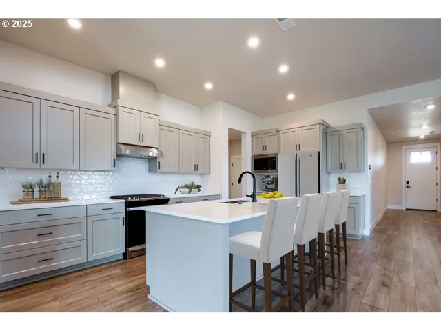a kitchen with stainless steel appliances granite countertop a sink a stove a dining table and chairs