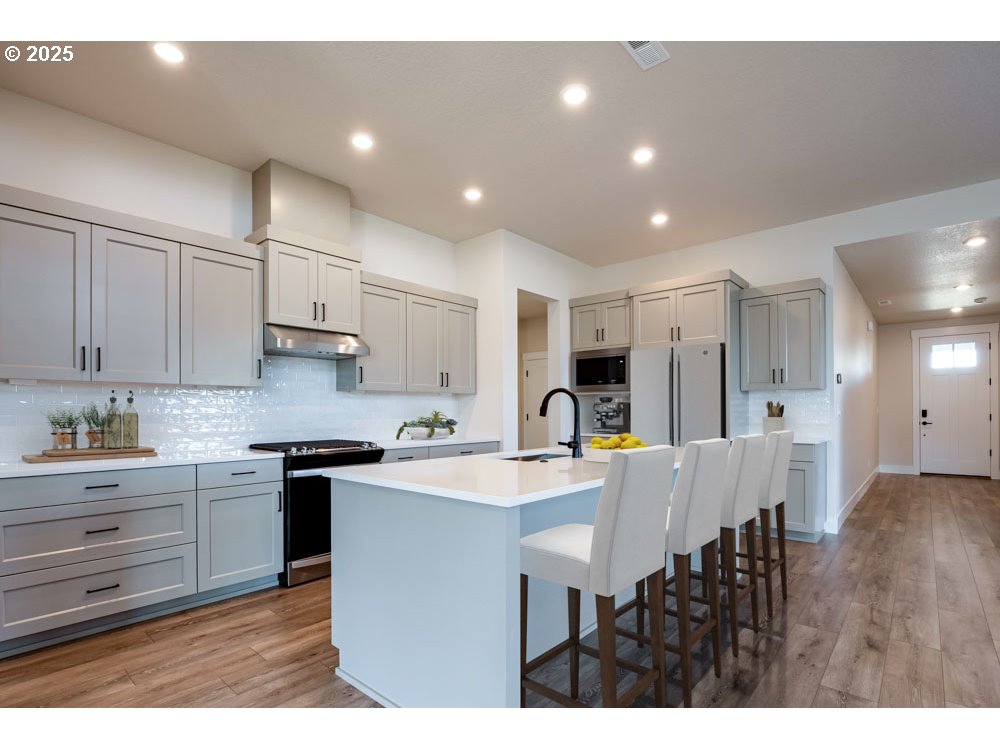 0 East Primavera Street Newberg, OR 97132 - Photo 4 of 8 a kitchen with stainless steel appliances granite countertop a sink a stove a dining table and chairs