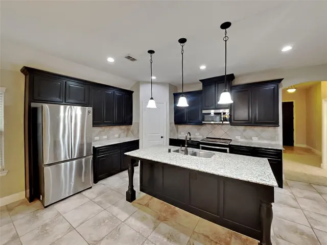 a kitchen with stainless steel appliances granite countertop a refrigerator a sink and a microwave