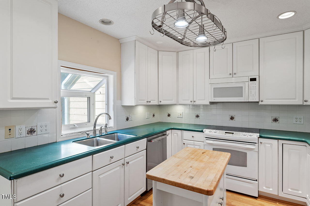 3124 Coachman's Way Durham, NC 27705 - Photo 13 of 30 a kitchen with a sink dishwasher and white cabinets with wooden floor