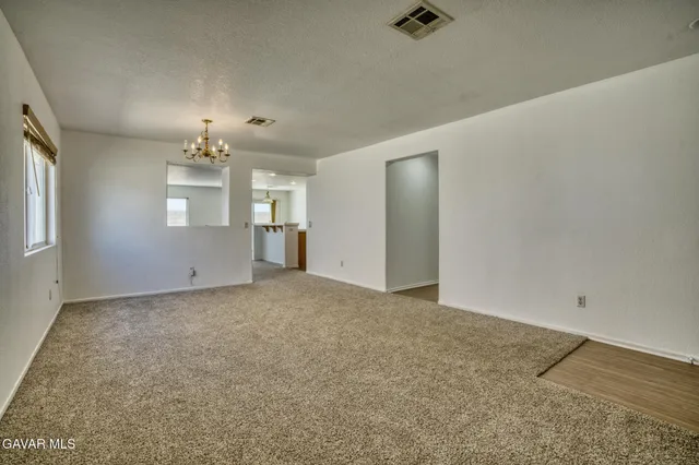 an empty room with chandelier fan and windows
