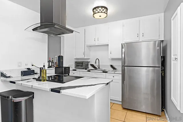 a kitchen with stainless steel appliances a refrigerator a sink a stove and white cabinets