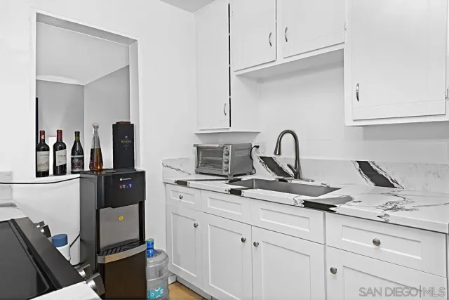 a kitchen with a sink and a stove with wooden floor