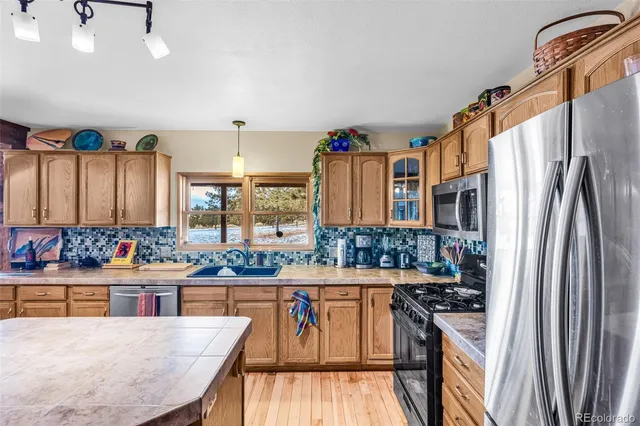 a kitchen with stainless steel appliances granite countertop a stove a sink and a refrigerator