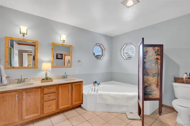 a bathroom with a granite countertop bathtub sink vanity mirror and toilet