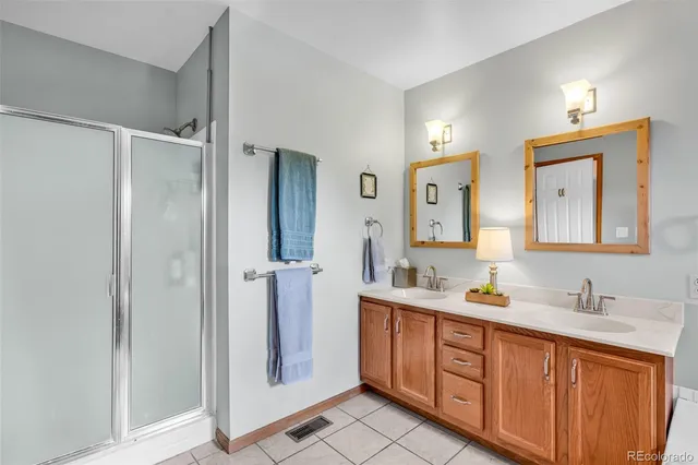 a spacious bathroom with a double vanity sink a mirror and a shower