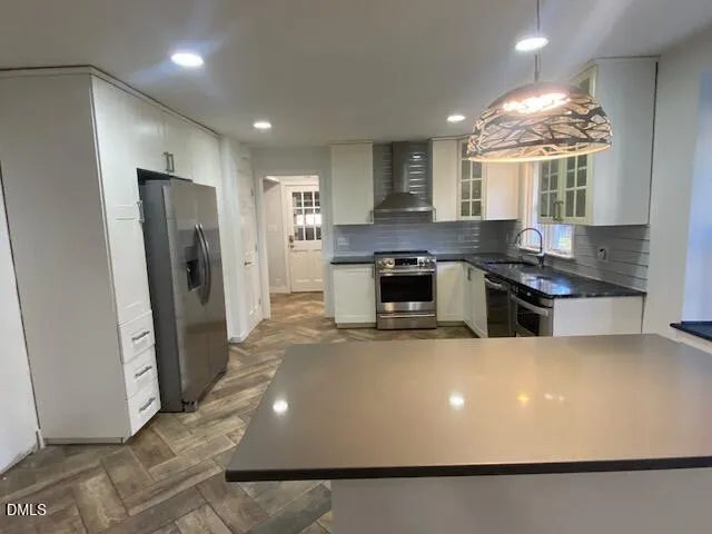 a large kitchen with stainless steel appliances a large counter top a stove a chimney a sink and a refrigerator