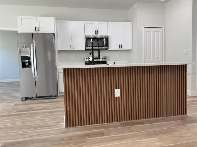 a kitchen with stainless steel appliances granite countertop white cabinets and refrigerator