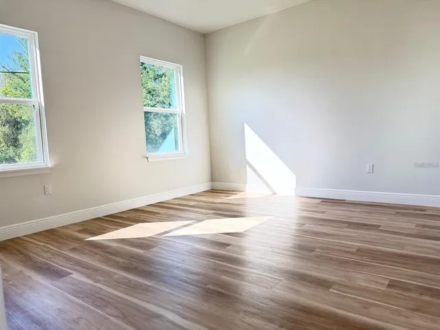 a view of empty room with wooden floor and fan