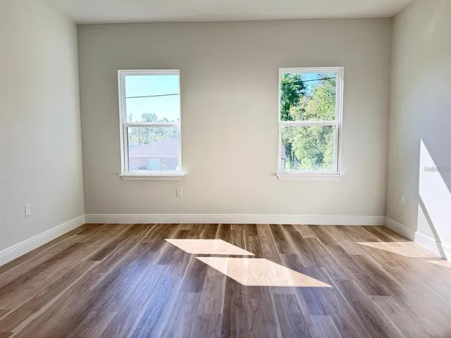 an empty room with wooden floor and windows