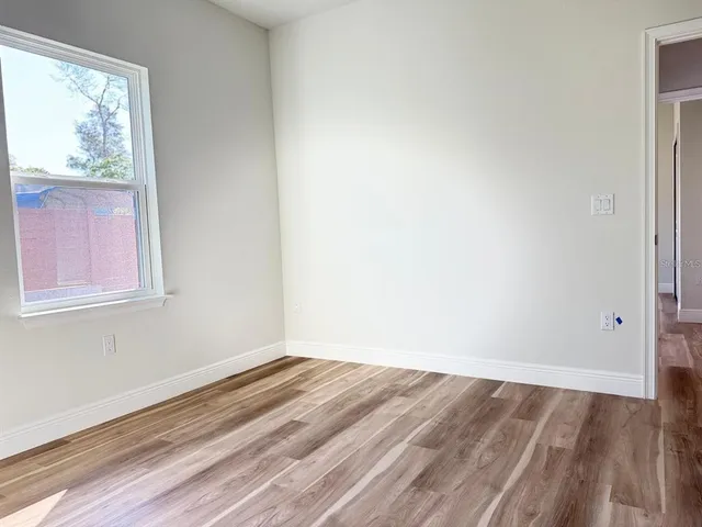 a view of empty room with wooden floor and fan