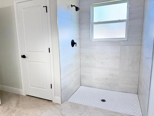 a bathroom with a bath tub a window and a glass door