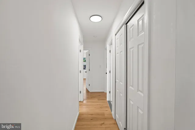 a view of a hallway with wooden floor and a bathroom