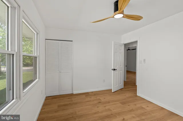 a view of an empty room with window wooden floor and a chandelier fan