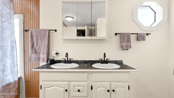 a bathroom with a granite countertop sink a mirror and shower