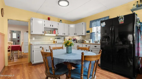 a kitchen with stainless steel appliances a refrigerator a stove a dining table and chairs with wooden floor