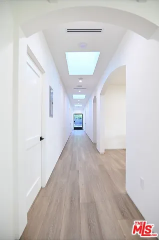 a view of a hallway with wooden floor and a bathroom
