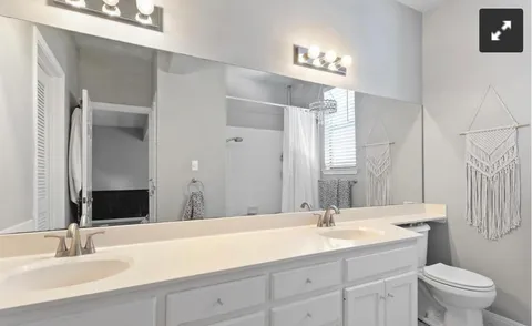 a bathroom with a granite countertop sink a toilet and a mirror