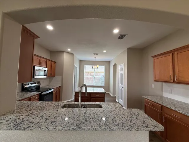 a living room with granite countertop furniture a flat screen tv and a refrigerator