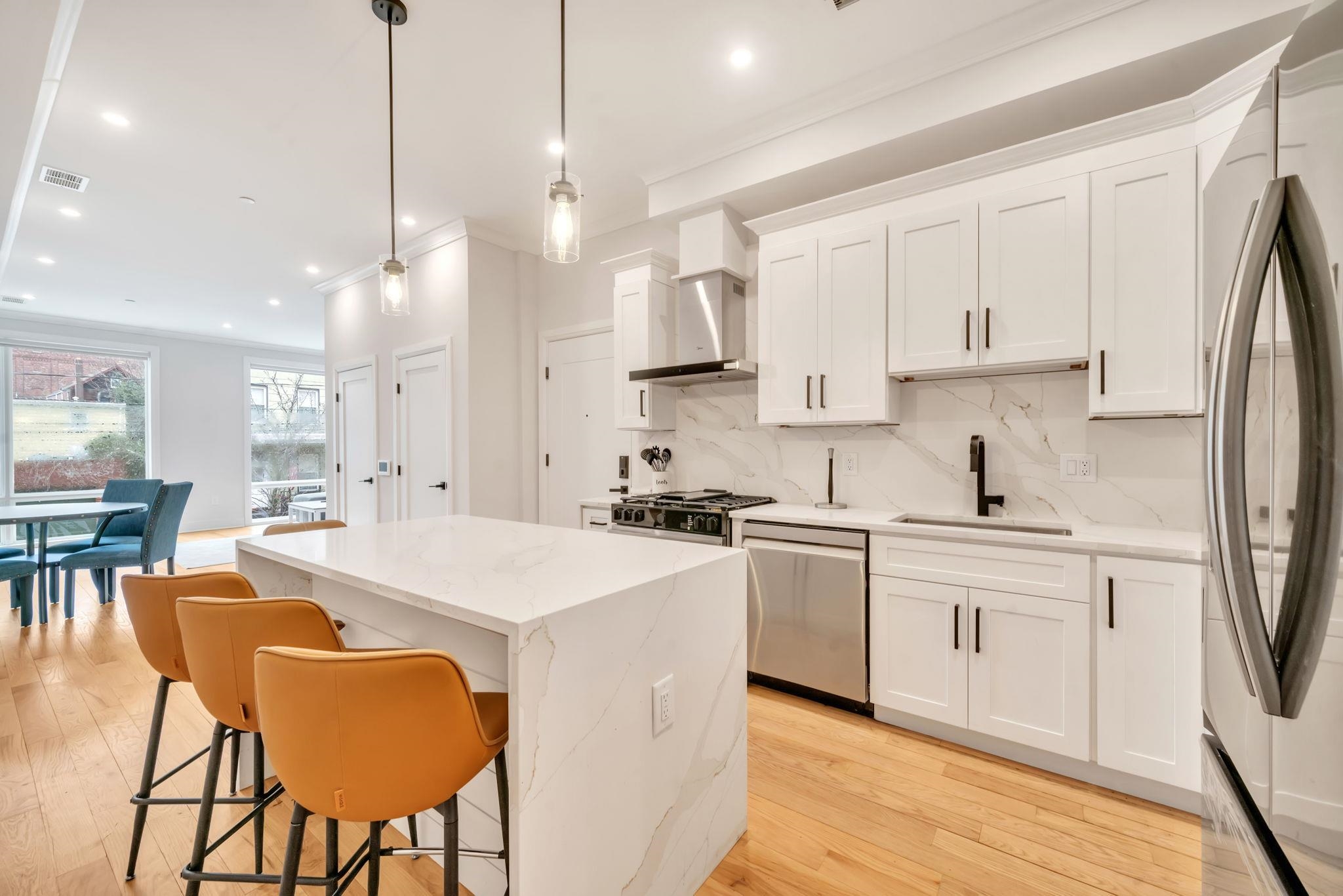 136 35th Street, Unit 1 Union City, NJ 07087 - Photo 9 of 18 a kitchen with stainless steel appliances kitchen island a table chairs sink and cabinets