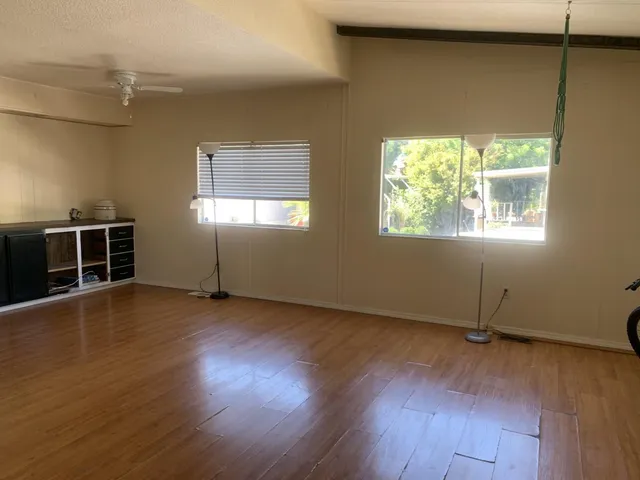 an empty room with wooden floor and windows