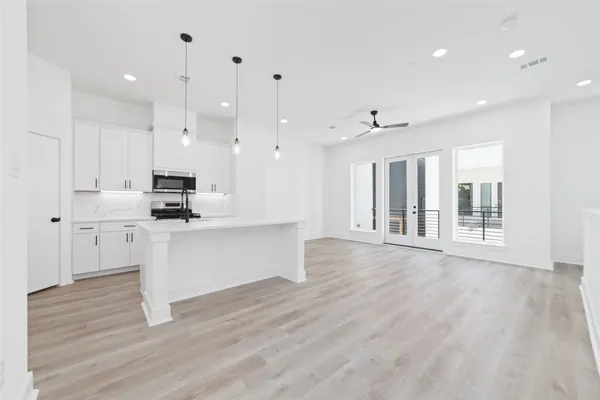 a large white kitchen with lots of counter space wooden floor and appliances