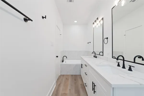a spacious bathroom with a double vanity sink a mirror and a bathtub