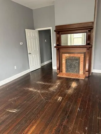 an empty room with wooden floor fireplace and windows