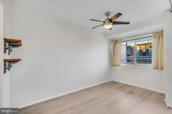 a view of empty room with wooden floor and fan