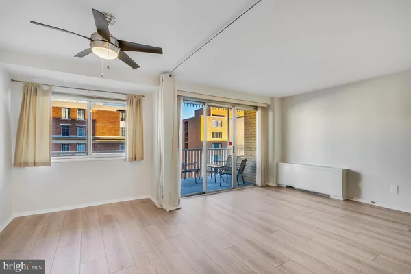a view of empty room with wooden floor and fan