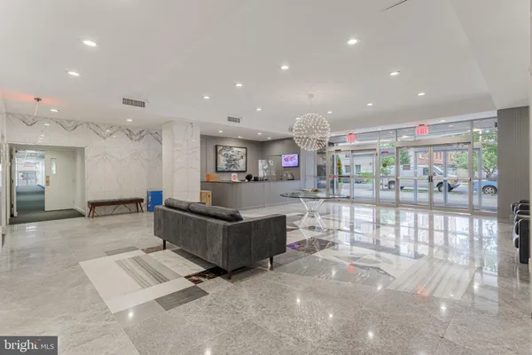 a living room with stainless steel appliances furniture a chandelier and a kitchen view