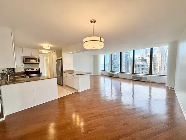 a view of a kitchen with a stove wooden cabinets and a living room