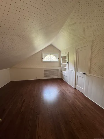 an empty room with wooden floor cabinet and windows
