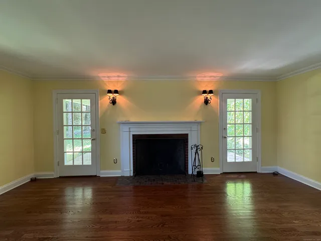 an empty room with wooden floor fireplace and windows