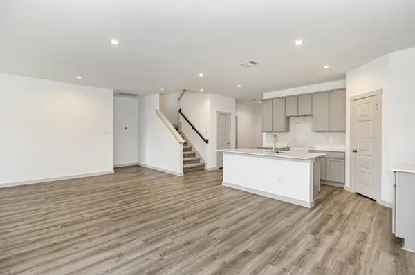 a view of a kitchen with kitchen island white cabinets wooden floor and stainless steel appliances