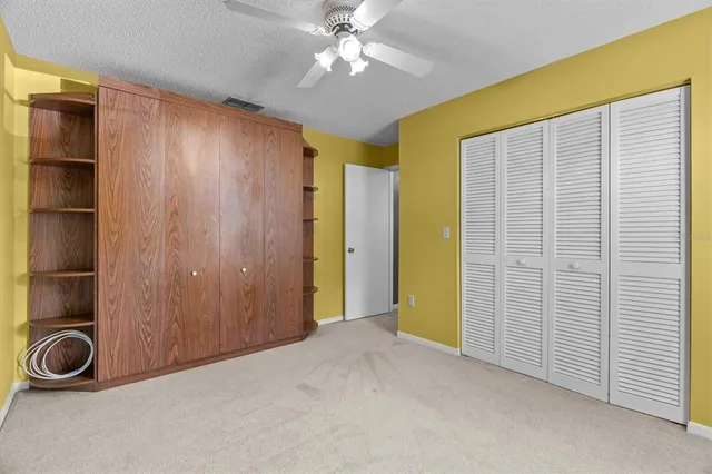 a view of a big room with windows and chandelier fan