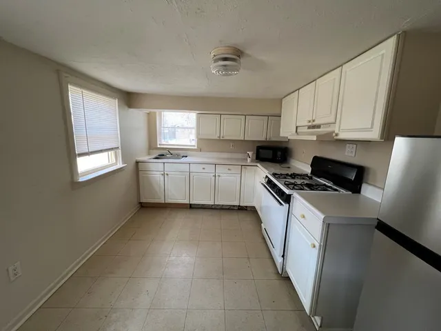 a kitchen with granite countertop cabinets stainless steel appliances a sink and a window