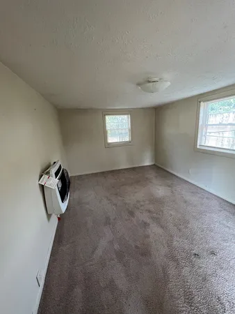 an empty room with windows and cabinet