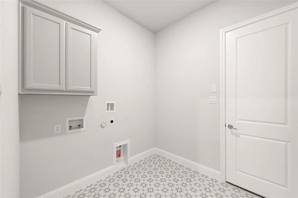 4021 Alpine Street Midlothian, TX 76065 - Photo 15 of 18 Utility space featuring patterned tile flooring, a white paneled door with brushed nickel hardware, and a built-in upper cabinet with crown molding