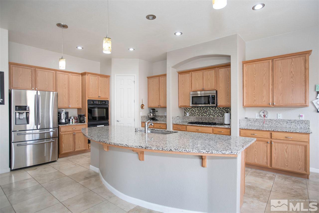 1675 Greycrest Way Reno, NV 89521 - Photo 7 of 25 a large kitchen with granite countertop a large counter top stainless steel appliances and cabinets