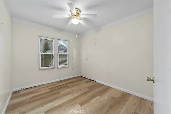 a view of empty room with wooden floor and fan